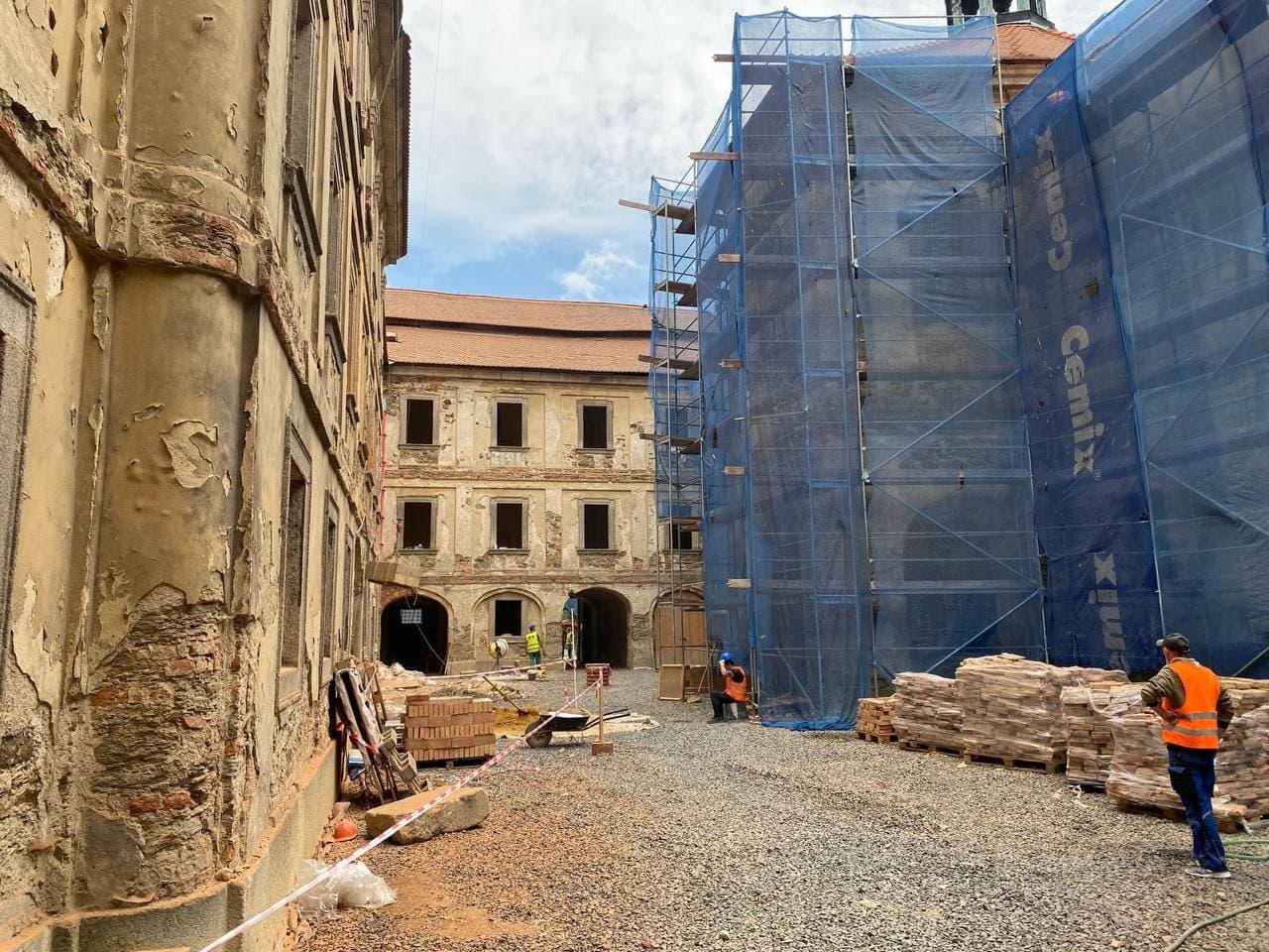 Obnova fasád historického areálu — lešení a probíhající práce